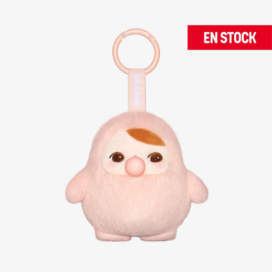 Llavero de peluche coleccionable de la serie Pucky Bubble, con diseño redondeado en tono rosa claro, nariz de burbuja rosada y expresión dulce. Tiene ceja marrón en forma de mechón y grandes ojos brillantes. Cuelga de una anilla rosada con cinta que dice "BEANIE". En la esquina superior derecha aparece una etiqueta roja con el texto "EN STOCK"