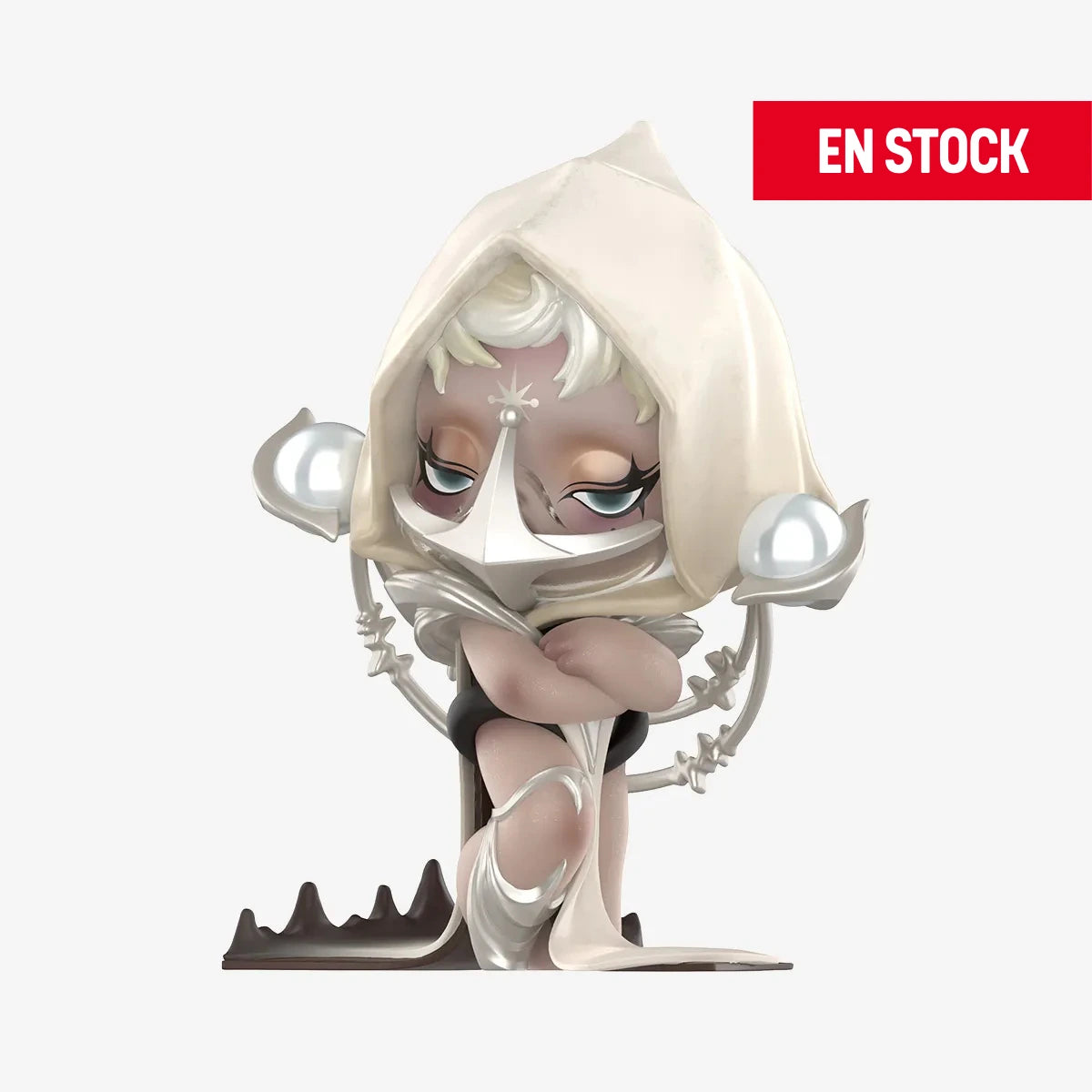 Figura coleccionable de SKULLPANDA de la serie "The Sound", representando a un personaje con una expresión seria y mirada intensa, vestido con una capucha blanca y adornos metálicos en forma de esferas y estructuras futuristas. Está sentado con los brazos cruzados sobre una base oscura. En la esquina superior derecha aparece una etiqueta roja con el texto "EN STOCK"